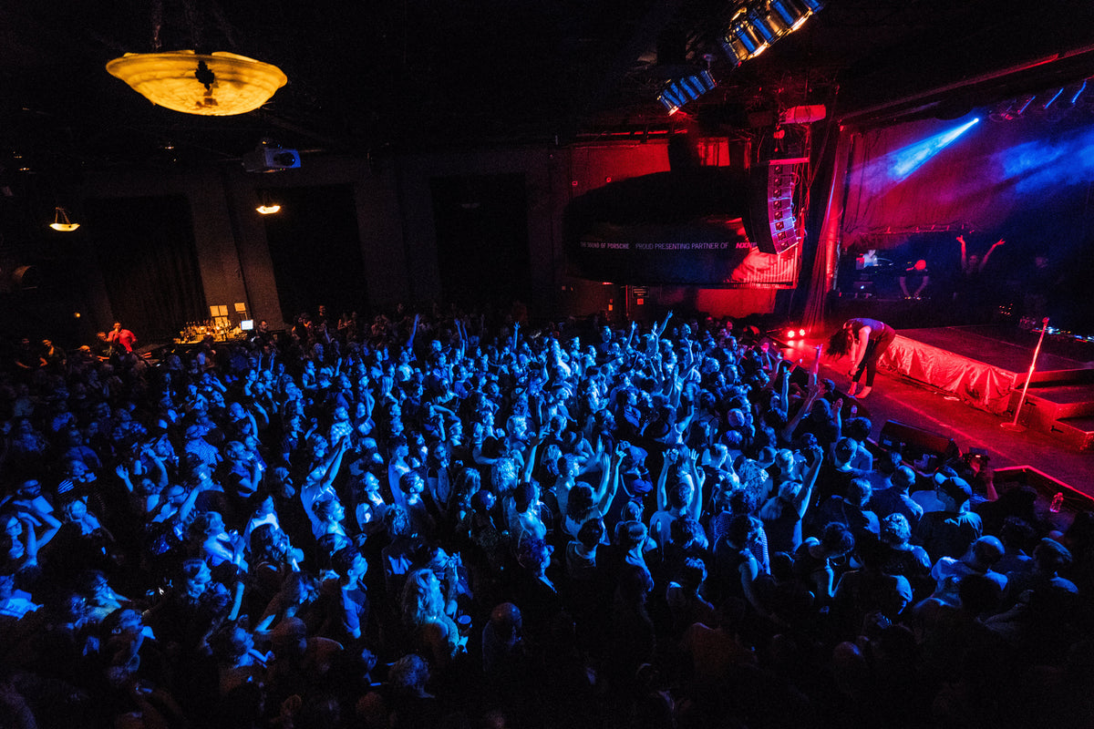 Performer silhouetted against red stage lights over a crowd